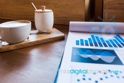 Coffee Cup  On A Table With Laptob And Graph Finance Diagram In Stock Photo