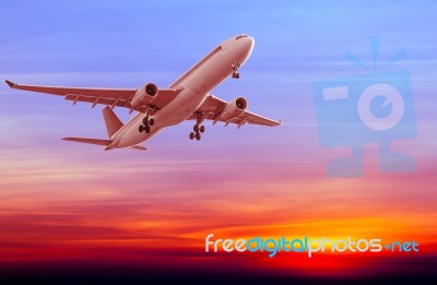 Commercial Airplane Flying At Sunset Stock Photo