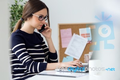 Confident Young Woman Working In Her Office With Laptop Stock Photo