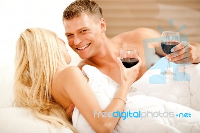 Couple Enjoying Wine In Bed Stock Photo