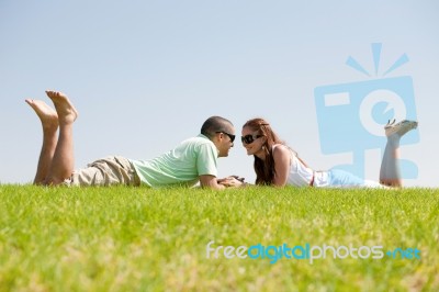 Couple Laying On Grass Lawn Stock Photo