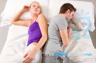 Couple Lying In Bed After Argument Stock Photo