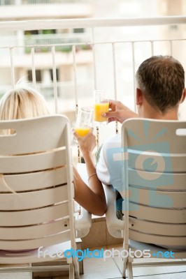 Couple On Balcony Drinking Juice Stock Photo