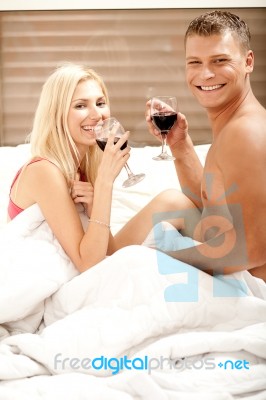 Couple Sharing A Drink In Bedroom Stock Photo