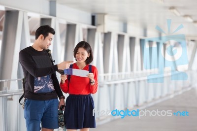 Couples Of Younger Traveling Man And Woman Looking To Traveler Guide Book On Location Stock Photo