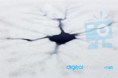 Cracks And Hole In Ice On Pond Stock Photo