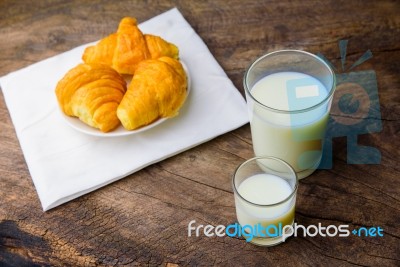 Croissant On Dish With Milk On Old Wooden Table Stock Photo