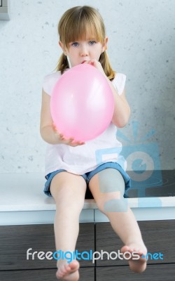 Cute Little Girl Inflating A Pink Balloon In The Kitchen Stock Photo Cute Little Girl Inflating A Pink Balloon In The Kitchen Stock Photo