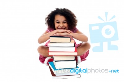 Cute School Girl Leaning Over Stack Of Books Stock Photo