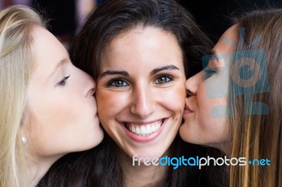 Cute Smiling Girl Kissed On The Cheeks By Her Friends Stock Photo