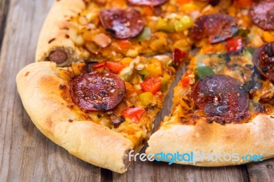 Delicious Baked Salami Pizza Served On Rustic Wooden Table Stock Photo