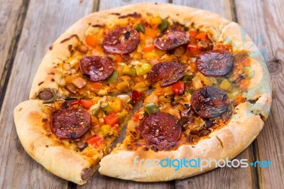 Delicious Baked Salami Pizza Served On Rustic Wooden Table Stock Photo