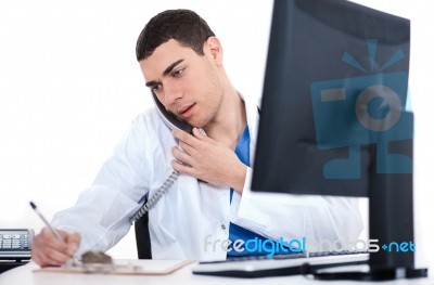 Doctor Making Notes Of The Conversation Over Phone Stock Photo