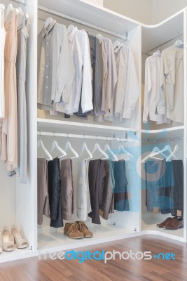 Dress And Shirts Hanging On Rail In White Wardrobe Stock Photo