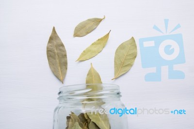 Dried Bay Leaves In Glass Jar On White Wooden Background Stock Photo