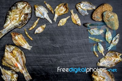Dry Fish With Sunny On Black Wooden Floor Stock Photo