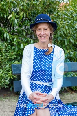 Dutch Woman In Old-fashioned Clothes Sitting On Bench In Park Stock Photo