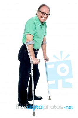 Elderly Man Walking With Help Of Crutches Stock Photo