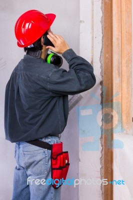 Engineer Man Wearing Hard Hat And Earmuffs While Having A Phone Stock Photo