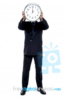 Executive Holding Up Wall Clock In Front Of His Face Stock Photo