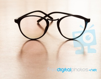 Eyeglasses With Reflection On Wooden Table Stock Photo