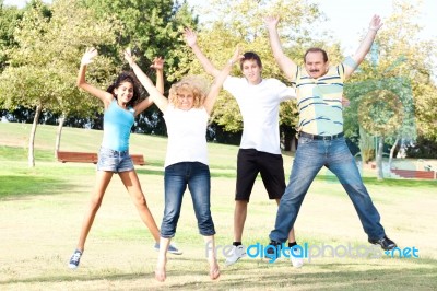 Family Jumping High In The Air On A Green Meadow Stock Photo