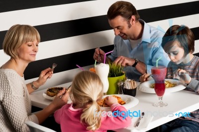 Family Of Four Having Meal In Restaurant Stock Photo