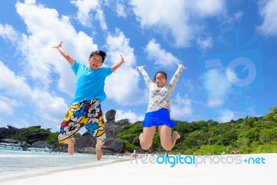 Father And Daughter Jumping On Beach At Thailand Stock Photo