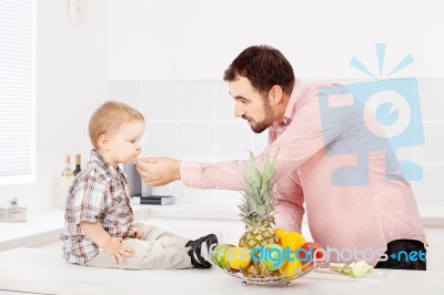 Father Feeding Child In Kitchen Stock Photo