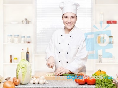 Female Chef Cutting Onions On The Cutting Board In Kitchen Stock Photo