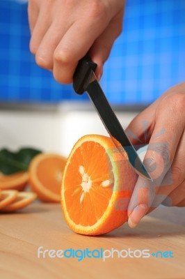 Female Chopping Juicy Orange On The Kitchen Stock Photo
