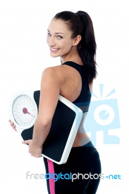 Female Fitness Trainer Holding Weighing Machine Stock Photo