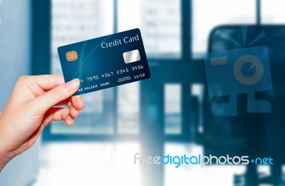 Female  Hand Holding Credit Card Against Business Office Backgro… Stock Photo