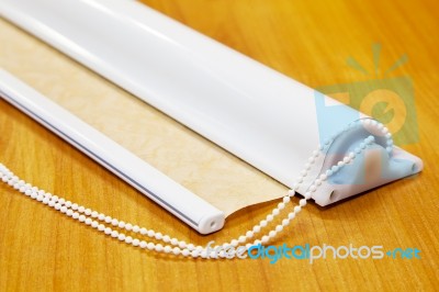 Fragment Of Roll Curtains In A Plastic Case On The Table Stock Photo