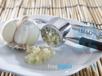 Fresh Garlic Crushed By Garlic Crusher On White Dish On Kitchen Stock Photo