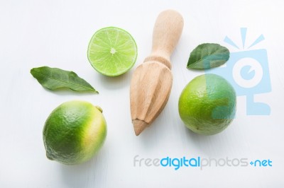 Fresh Limes And Wooden Juicer On White Background. Top View Stock Photo