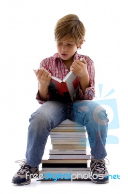 Front View Of Boy Sitting On Books Stock Photo