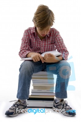 Front View Of Boy Sitting On Books On White Background Stock Photo Front View Of Boy Sitting On Books On White Background Stock Photo