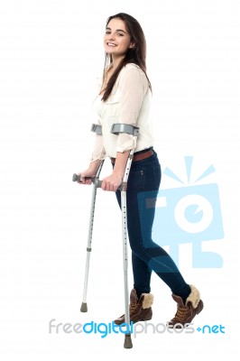 Full Length Portrait Of Young Girl Walking With Crutches Stock Photo