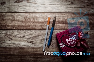 Gift Box And Pens On Wooden Plank Stock Photo