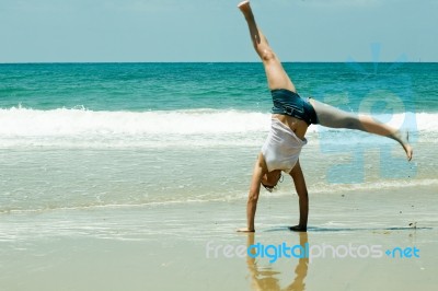 Girl Doing cartwheel At Beach Stock Photo