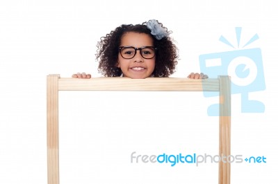 Girl Peeping From Behind White Writing Board Stock Photo