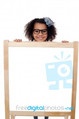 Girl Peeping From Behind White Writing Board Stock Photo