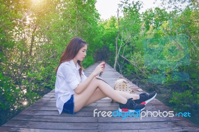 Girl Sitting Alone And Hand Holding Camera On A The Wooden Bridg… Stock Photo