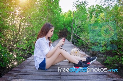 Girl Sitting Alone And Hand Holding Camera On A The Wooden Bridg… Stock Photo
