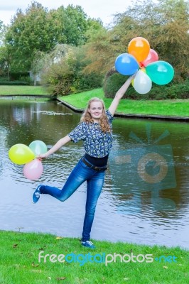 Girl Standing At Pond With Colored Balloons Stock Photo