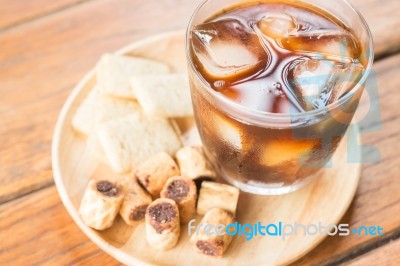 Glass Of Black Iced Coffee With Some Snack Stock Photo