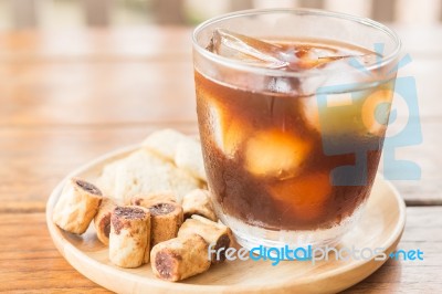 Glass Of Black Iced Coffee With Some Snack Stock Photo