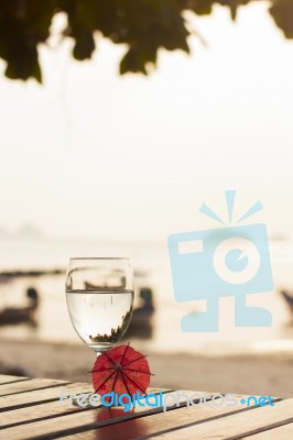 Glass Of Pure Water On A Dark Table On The Beach With A Palm Tre… Stock Photo