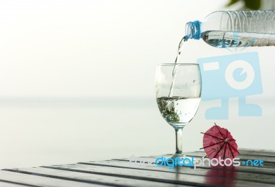 Glass Of Pure Water On A Dark Table On The Beach With A Palm Tre… Stock Photo